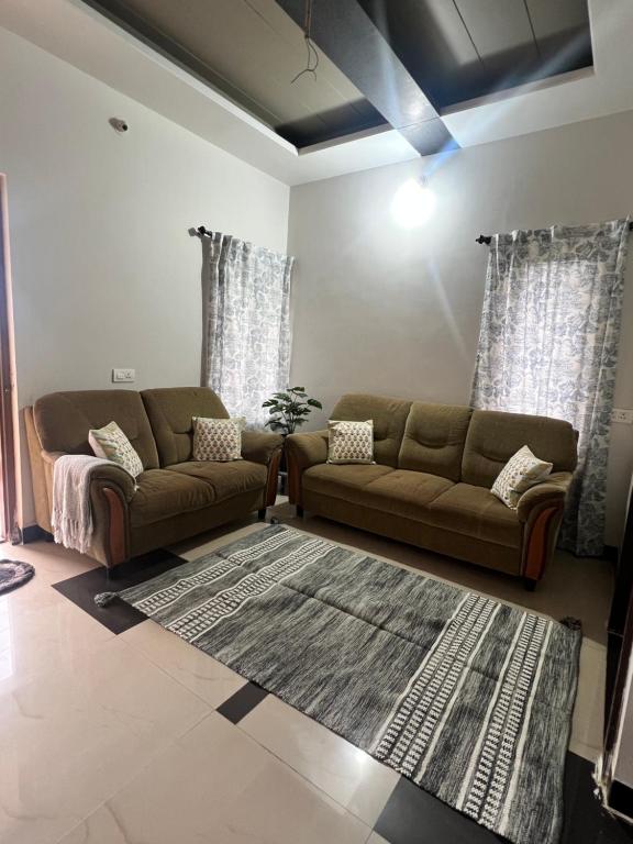 a living room with two couches and a rug at Villa Sereno Belgaum in Belgaum