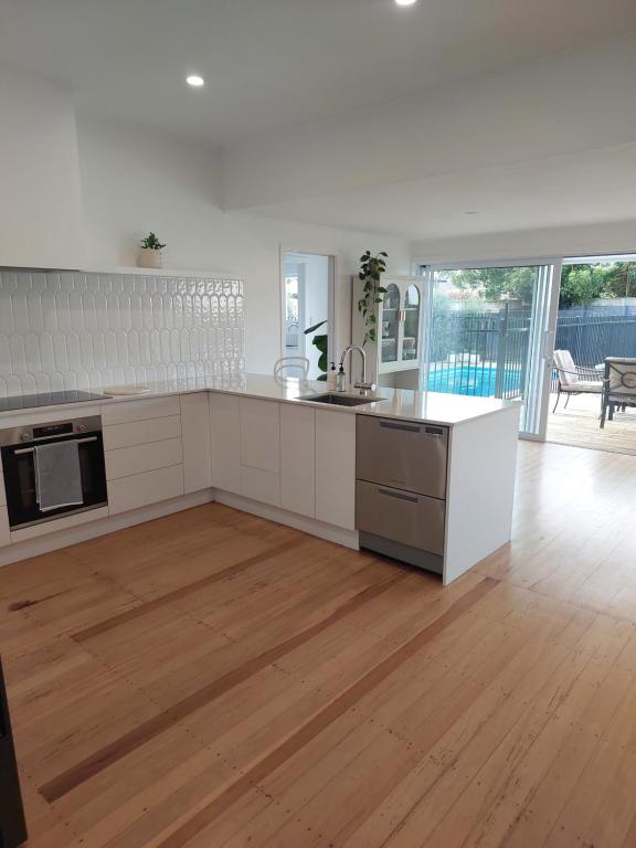 een keuken met witte kasten en een houten vloer bij Inner city Sanctuary in Gisborne