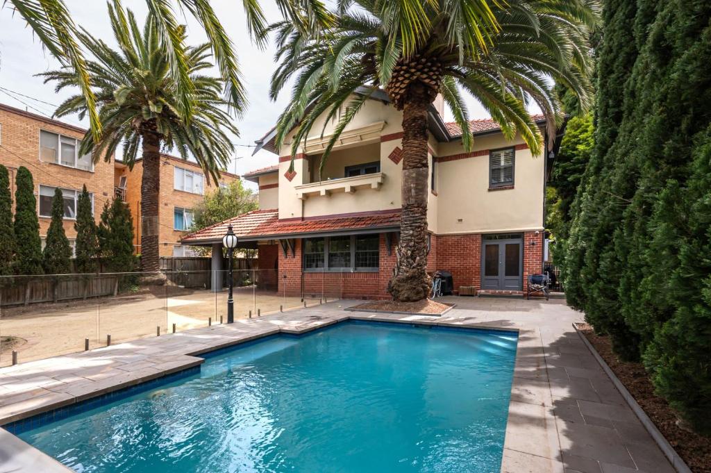een zwembad voor een huis met palmbomen bij Poolside at Kindrogan - St Kilda in Melbourne