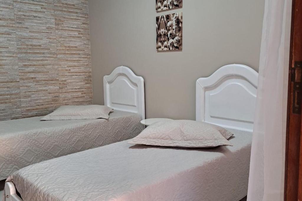 two beds in a room with white walls at Quarto confortável em Diamantina in Diamantina