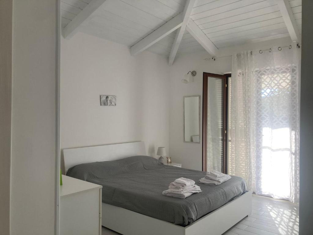 a white bedroom with a bed and a window at Rifugio di campagna in Varcaturo