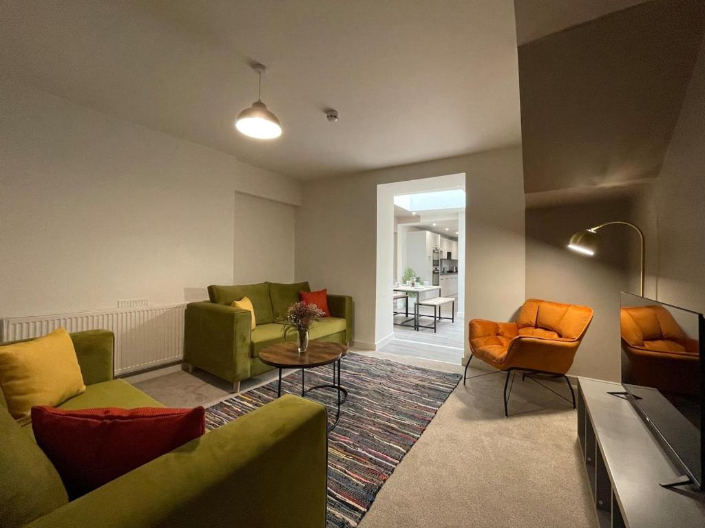 a living room with green furniture and orange chairs at Newly Renovated House in Aberystwyth Town Centre in Aberystwyth