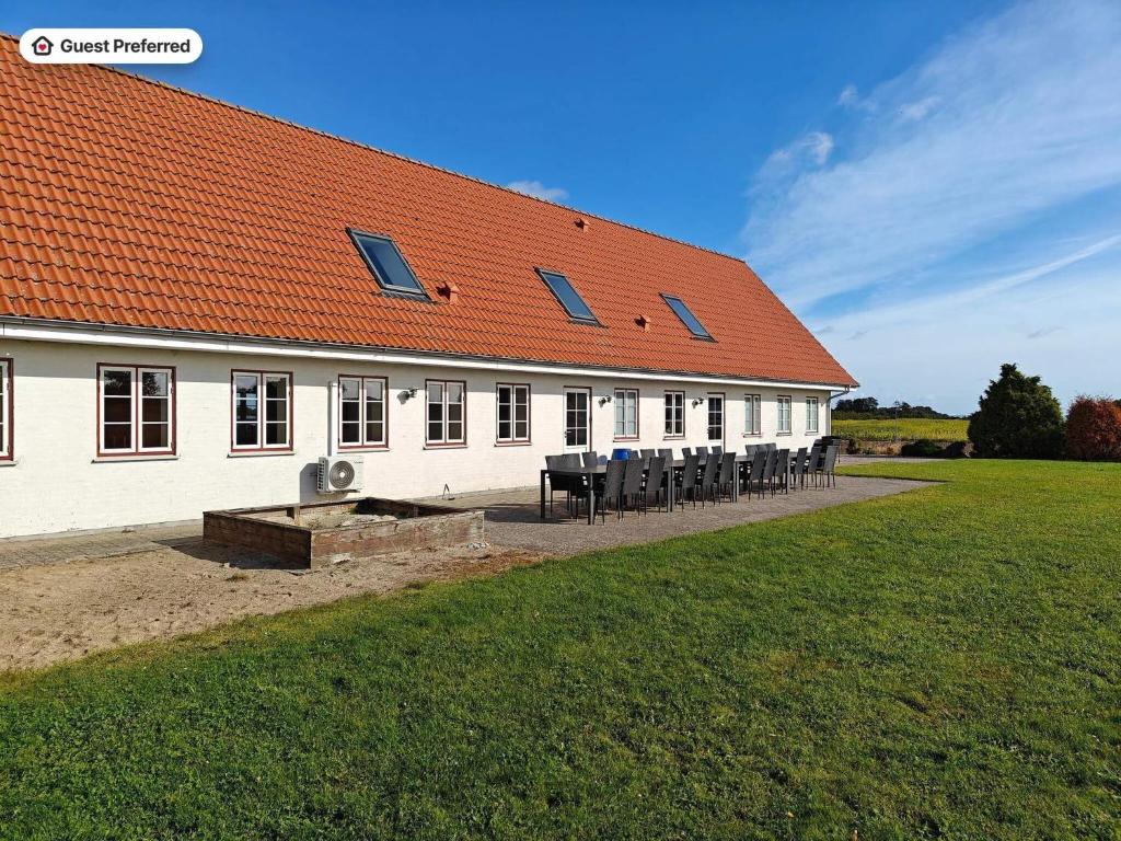 a white building with an orange roof with tables and chairs at 20 person holiday home in Nordborg-By Traum in Nordborg