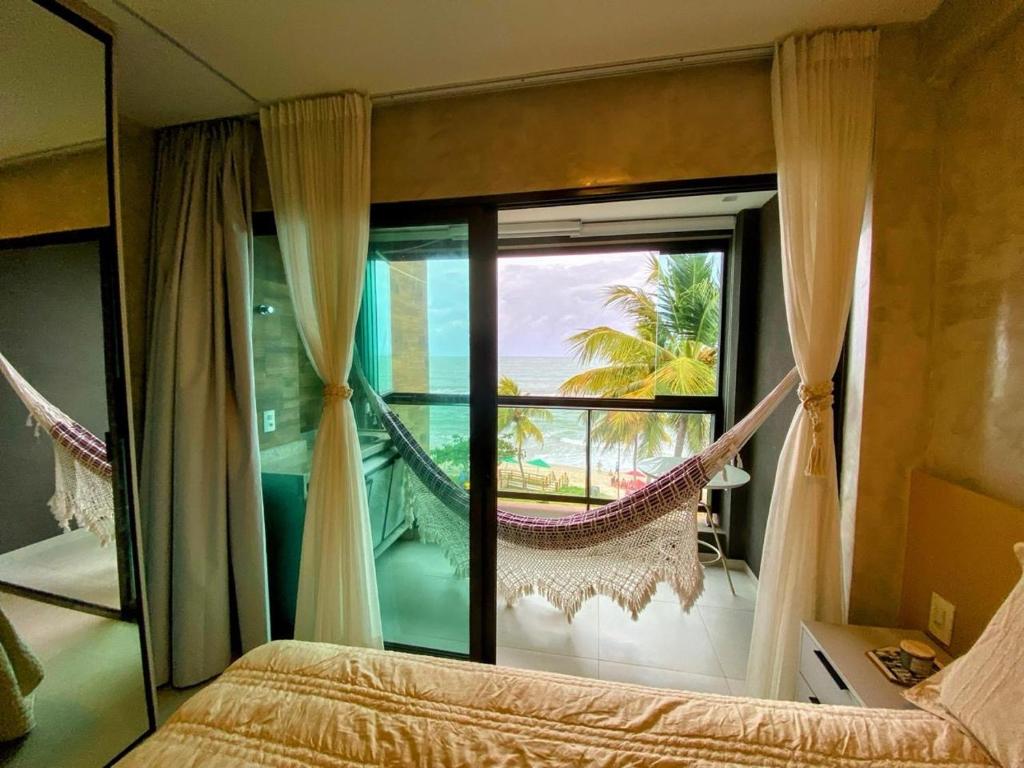 a bedroom with a hammock in front of a window at Kauai Beach Residence 403 in Tamandaré