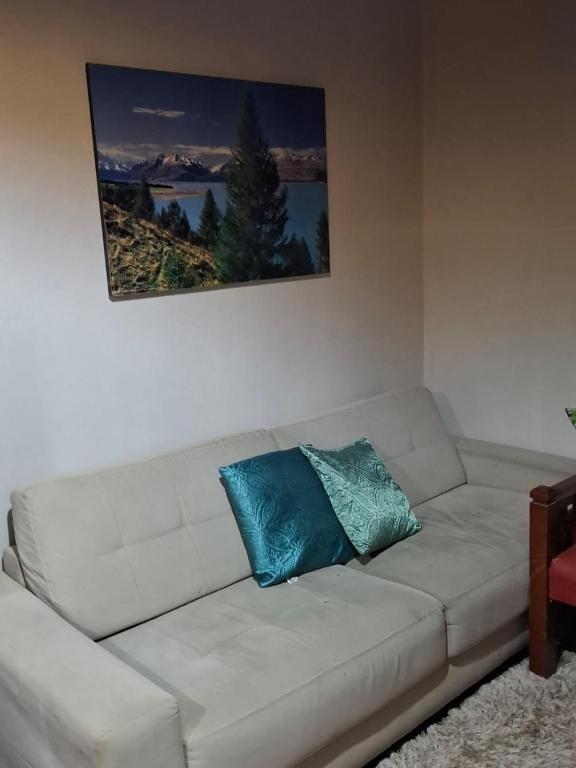 a white couch with two blue pillows on it at Chalé Dedo de Deus in Guapimirim