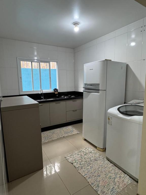 cocina blanca con nevera y fregadero en Casa 2 dormitórios, en Passo de Torres