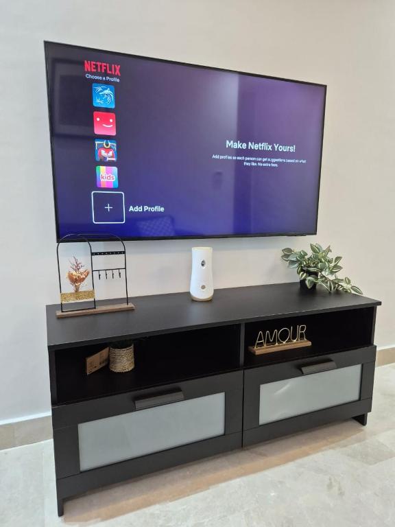 a flat screen tv sitting on top of a black entertainment center at Bright Cozy Escape Walk to CFC Self Check-in in Oulad Akkou