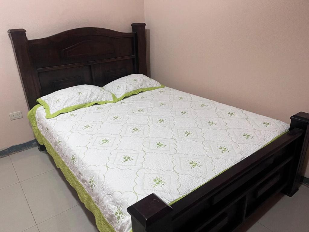 a bed with a wooden headboard with a white bedspread and pillows at Apartment near the Río Niño in Upala