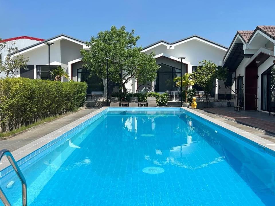 a blue swimming pool in front of some houses at Sandy Clay Bungalows in Sihanoukville