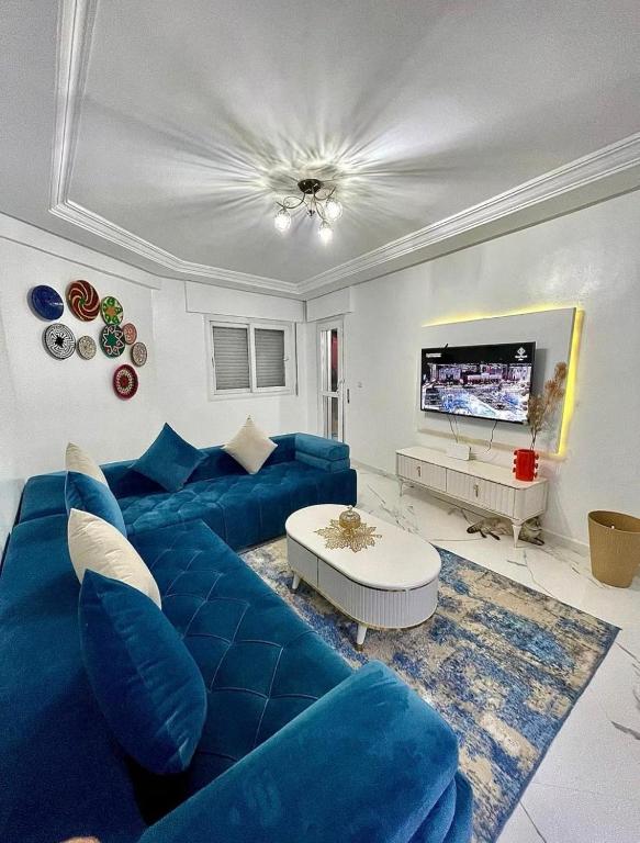 a living room with a blue couch and a tv at Seaside 1 min From Beach & Train Station in Tangier