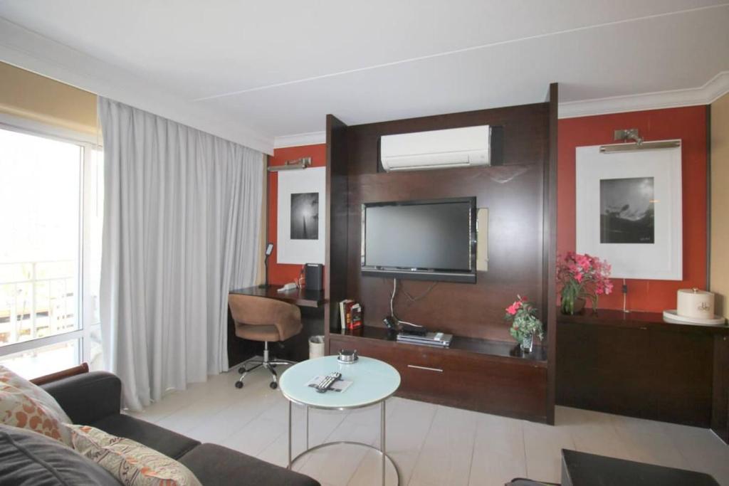 ein Wohnzimmer mit Sofa und Fernseher in der Unterkunft Waikiki - Resort amenities, walk to the beach! in Honolulu