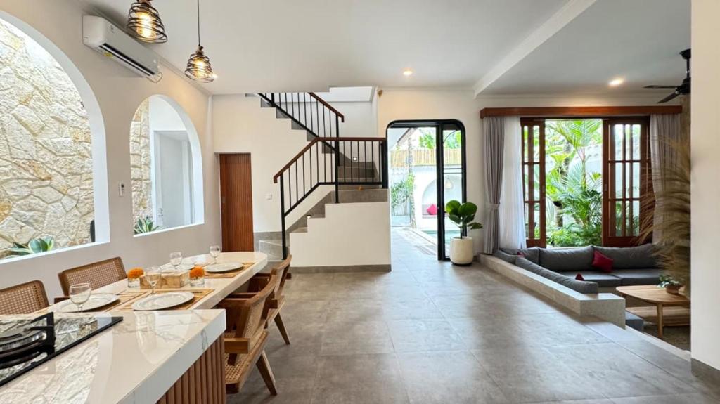 a kitchen and dining room with a staircase and a living room at Candra Villa Kedungu in Tanah Lot