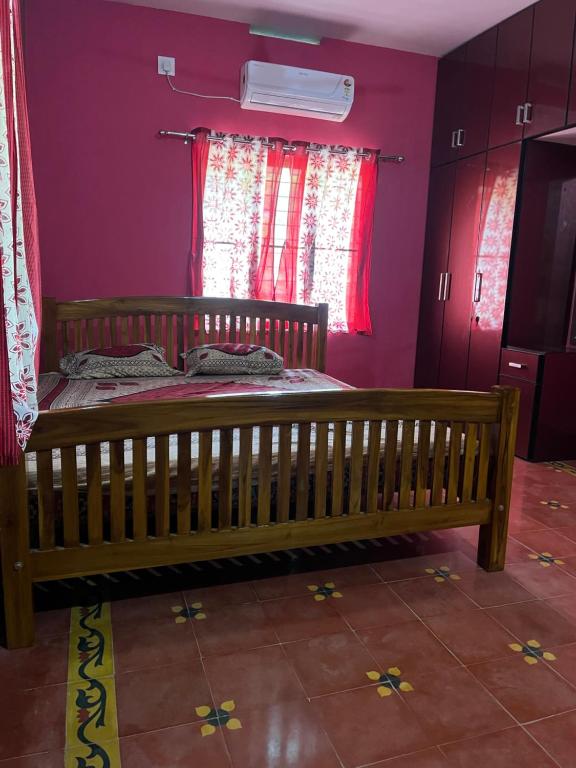a wooden bed in a room with purple walls at Tharissu Potta Rassey Farm House in Kollengode