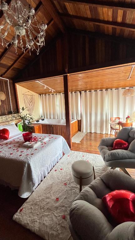 a bedroom with a bed and two couches and a chandelier at Cabana com banheira de Hidro e vista para o mar, privativa e tranquila localização excelente in Florianópolis