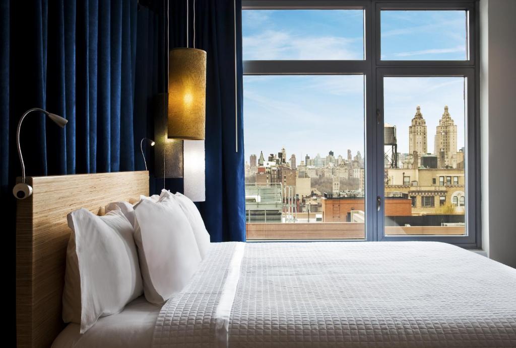 a bedroom with a large window with a view of the city at Arthouse Hotel in New York