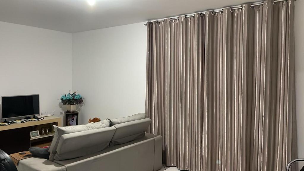Una sala de estar con un sofá y una cortina. en Quarto Moderno e aconchegante para hospedagem, en Foz do Iguaçu