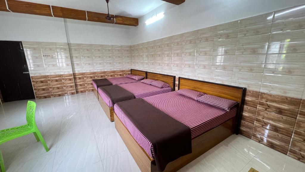 two beds in a room with a green chair at Singaravelu rooms in kāraikāl