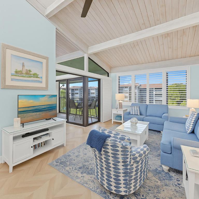 a living room with a blue couch and a tv at Beachfront Retreat 2 Bikes Sleeps 6 #443 in Sanibel