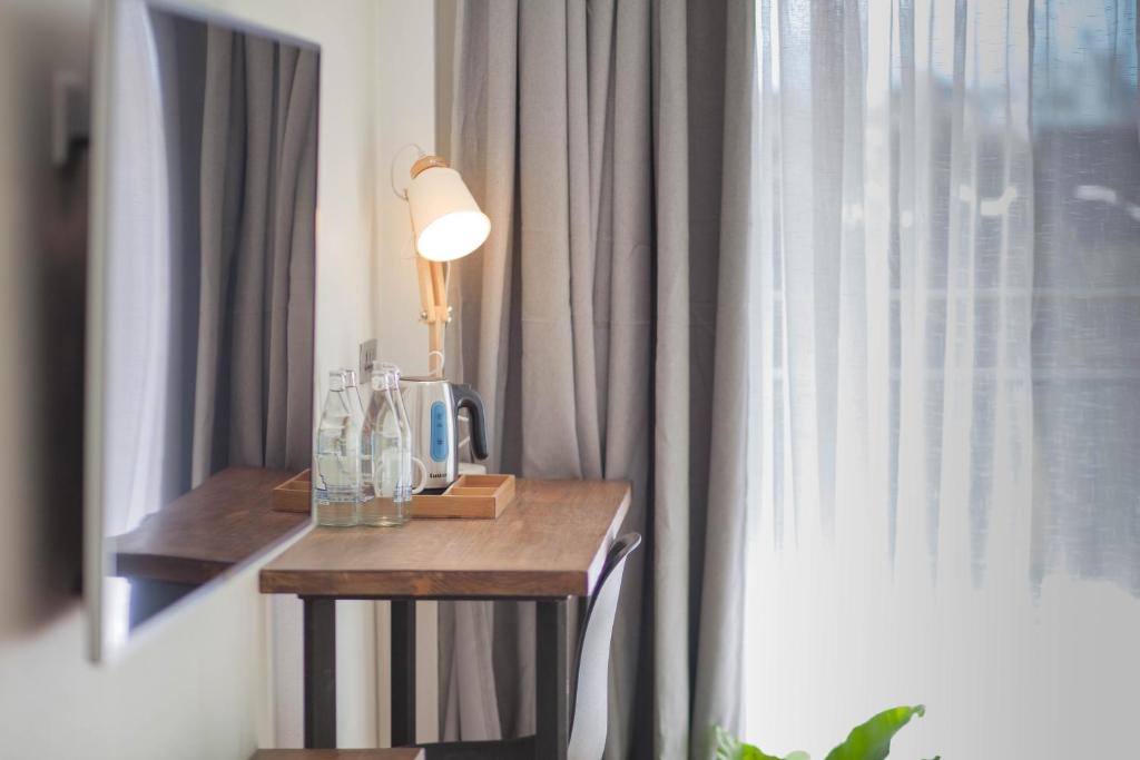 A compact in-room desk beside a curtained window, equipped for drinks and light work.