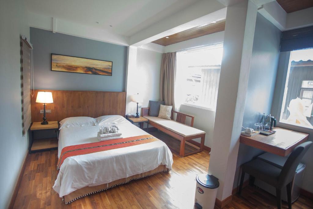 A bright guest room with a double bed, window-side seating and a separate desk.