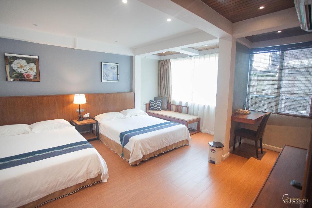 A bright twin room with two beds, a seating bench, and a compact work area.