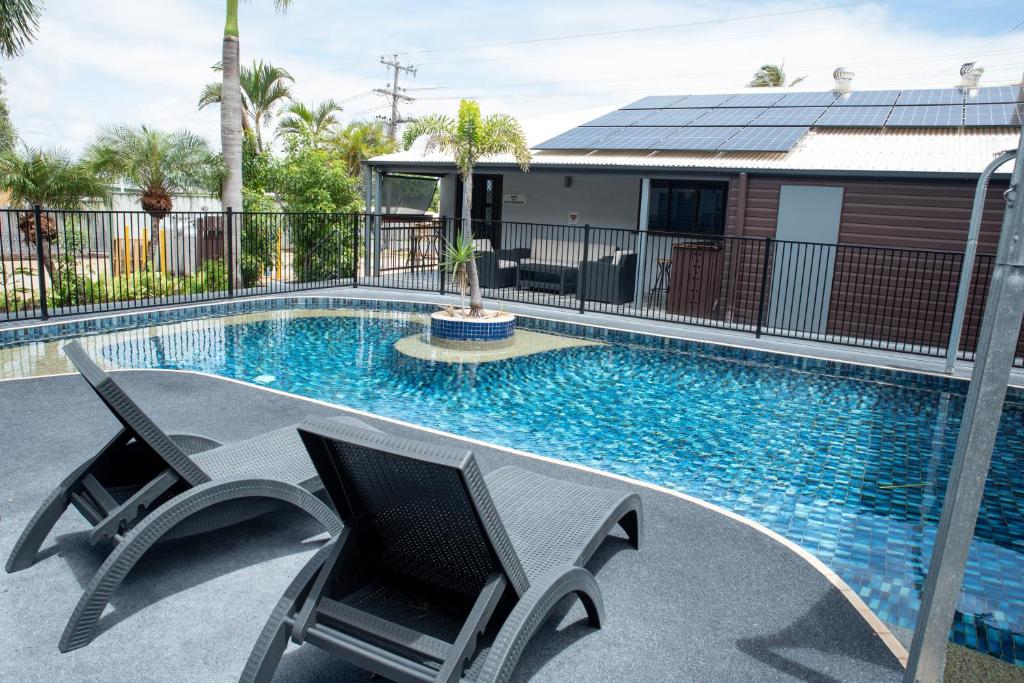 een zwembad met twee stoelen voor een huis bij River of Gold Motel in Cooktown