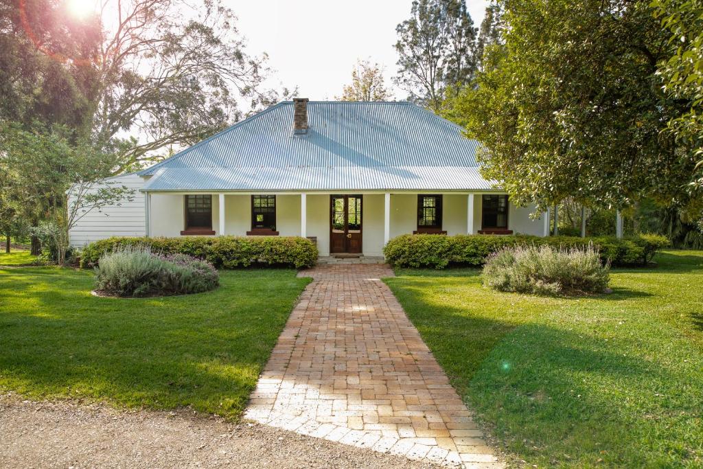 une maison blanche avec un chemin en briques devant elle dans l'établissement Old Duninald House - Historic Farmhouse Experience, à Paterson