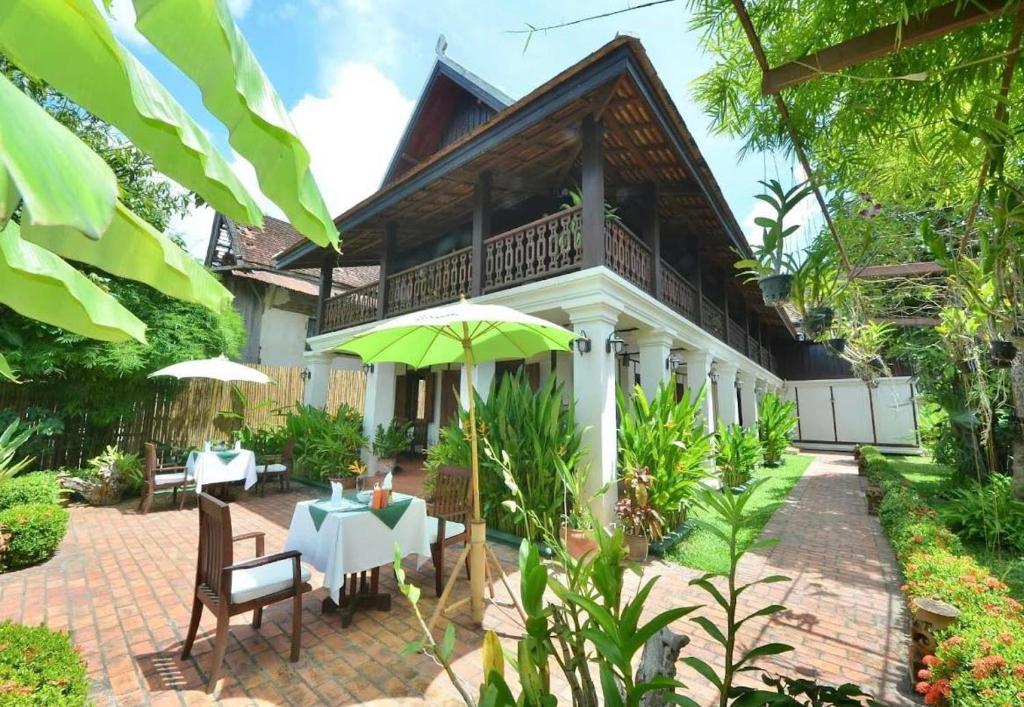 a house with a patio with a table and umbrella at Luang Prabang Residence - The Boutique Villa in Luang Prabang