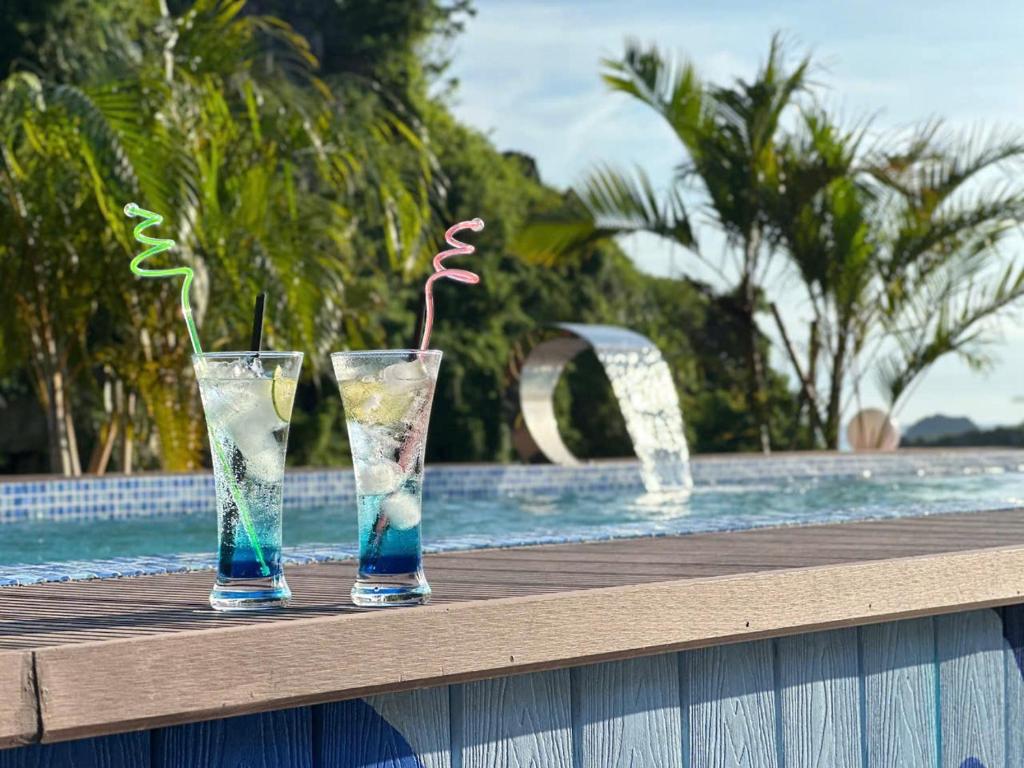 two glasses sitting on a table next to a swimming pool at Viet Hoa Hotel & Residence Cat Ba - Rooftop Pool in Cat Ba