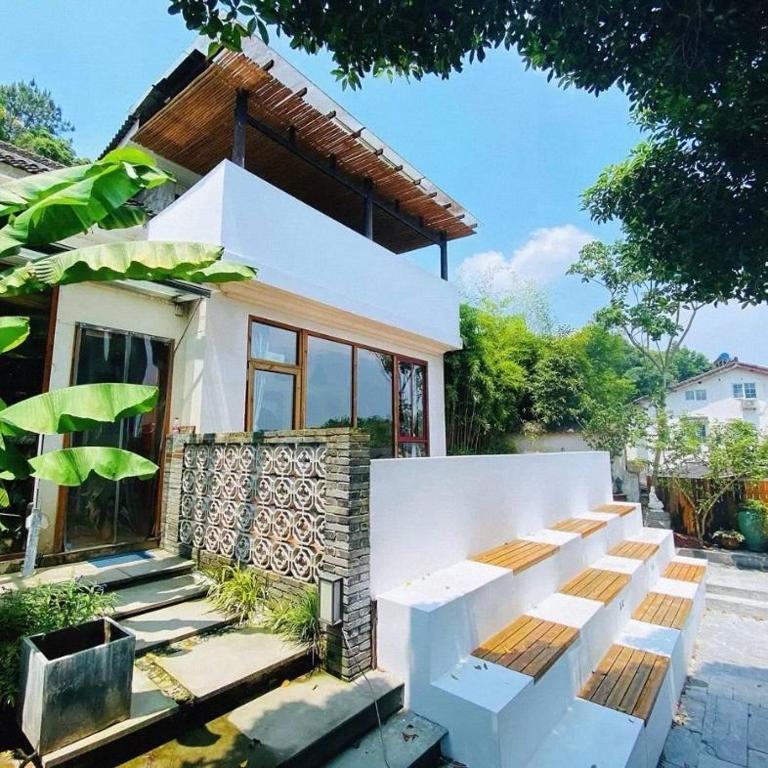 a white house with a bench in front of it at Dan’s Sea Guest House Hangzhou in Hangzhou
