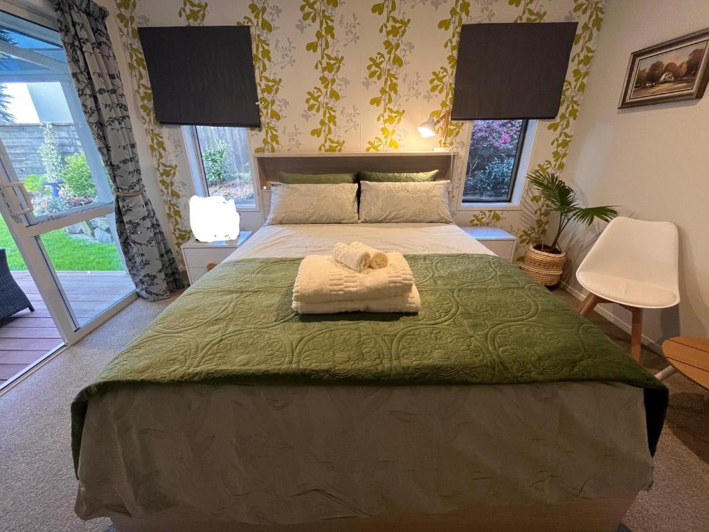 Hillpark Hideaway في أوكلاند: غرفة نوم مع سرير مع لحاف أخضر