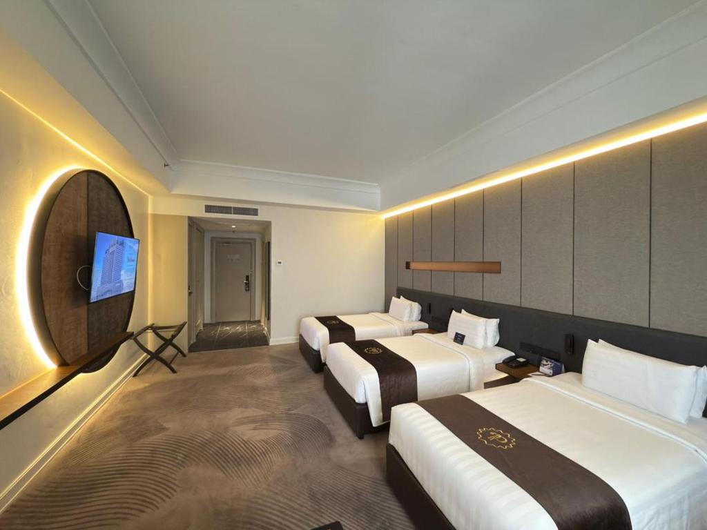 a hotel room with three beds and a flat screen tv at The Pearl Kuala Lumpur in Kuala Lumpur