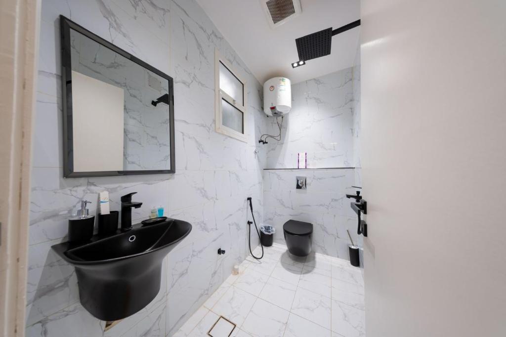 a bathroom with a black sink and white marble walls at Ohud Suites - أجنحة أحد in Riyadh