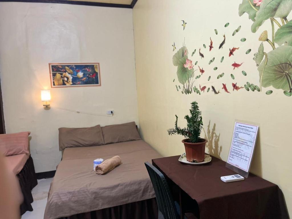 a room with two beds and a table with a plant at Subangan bayud3, Burgos central location in Burgos