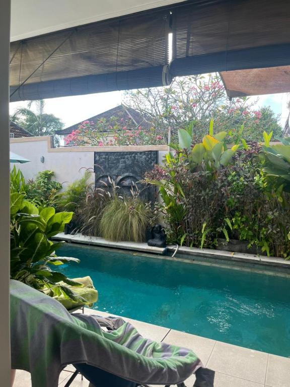 una piscina con un banco y algunas plantas en Villa Harmony Moon, en Denpasar