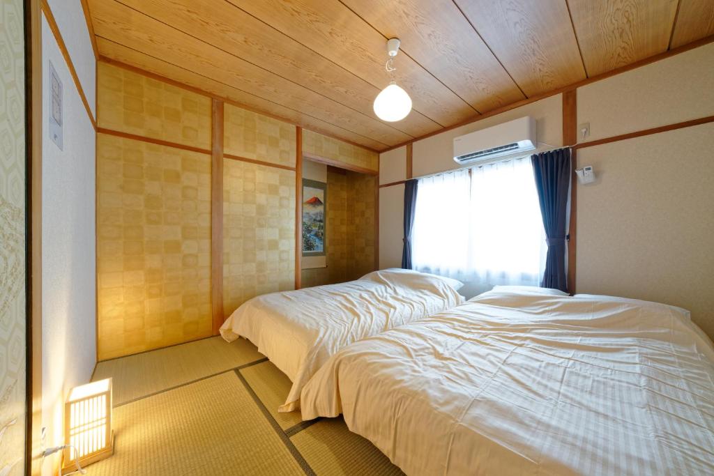 ein Schlafzimmer mit zwei Betten und einem Fenster in der Unterkunft 5 minutes on foot from the station, 20 minutes by train to Nagoya station, and it is a detached house, so families can use it with peace of mind! in Nagoya