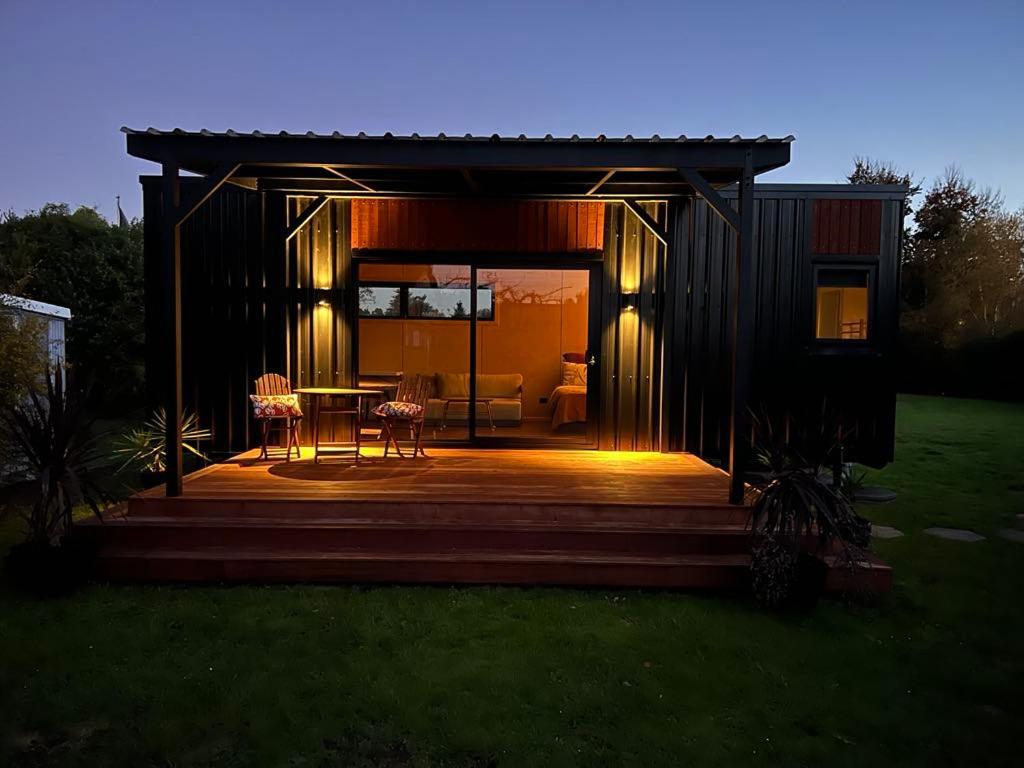a small cabin with a table and chairs on a deck at Kiln Side Cottage in Nelson