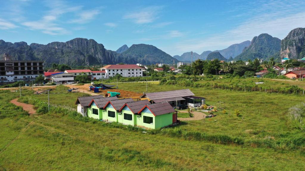 a village in a field with mountains in the background at sokxay guesthouse in Vang Vieng