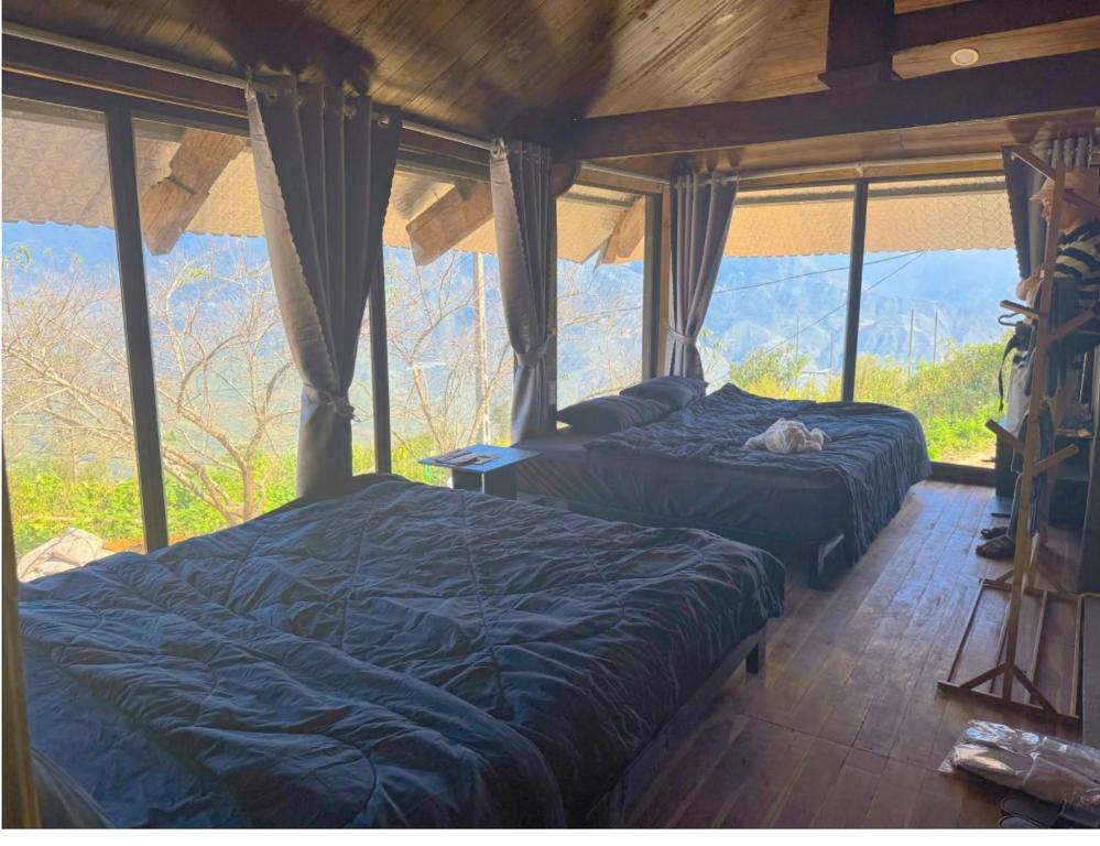 two beds in a room with a large window at Homestay26 in Bắc Yên
