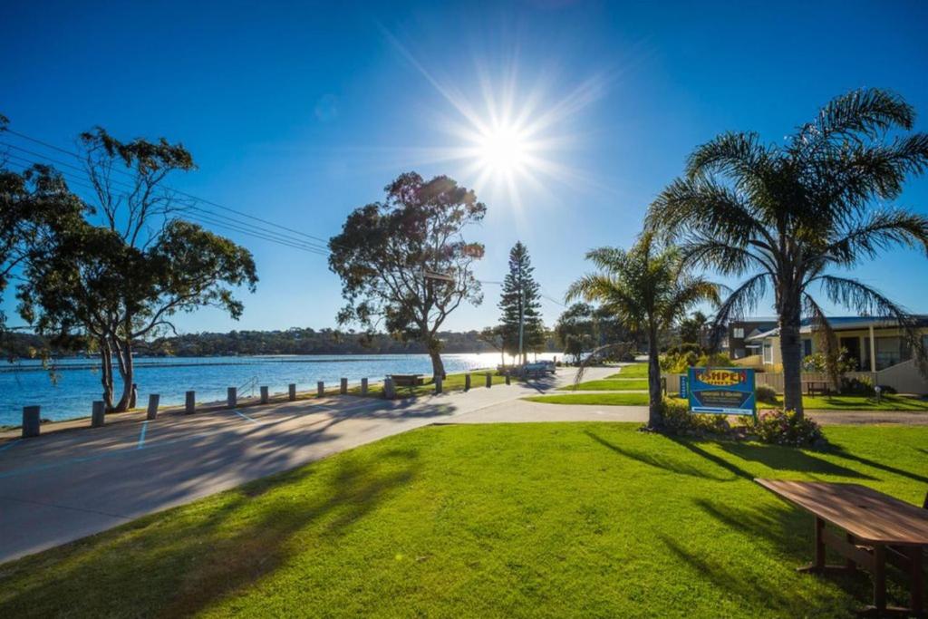 a park with a bench next to the water at Fishpen Holiday Units in Merimbula