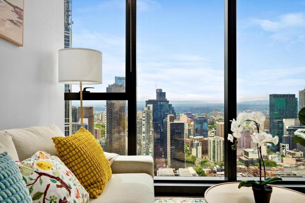 a living room with a couch and a large window at Home in the Sky 2BR Apt with City and River View in Melbourne