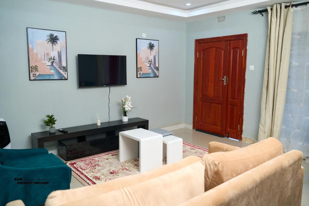 a living room with two chairs and a tv at K&M Luxury Apartments Solwezi in Solwezi
