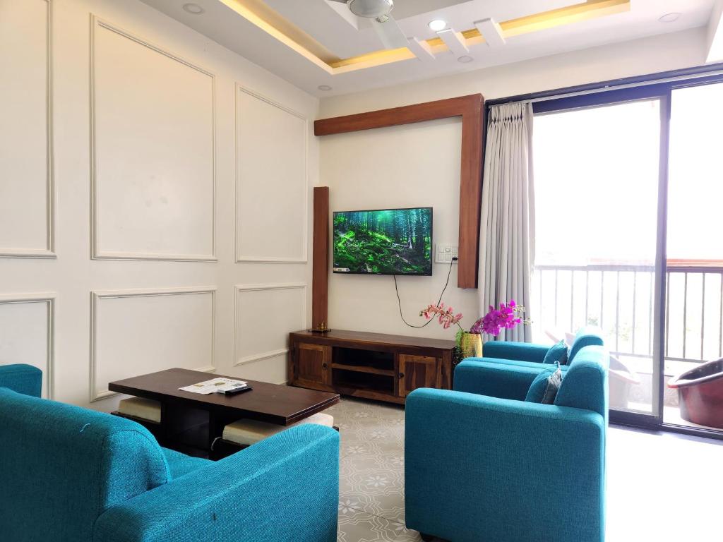 a living room with blue chairs and a flat screen tv at Romantic Goa Studio with Mangrove view - Walk to Candolim Beach, Ideal for Couples in Candolim