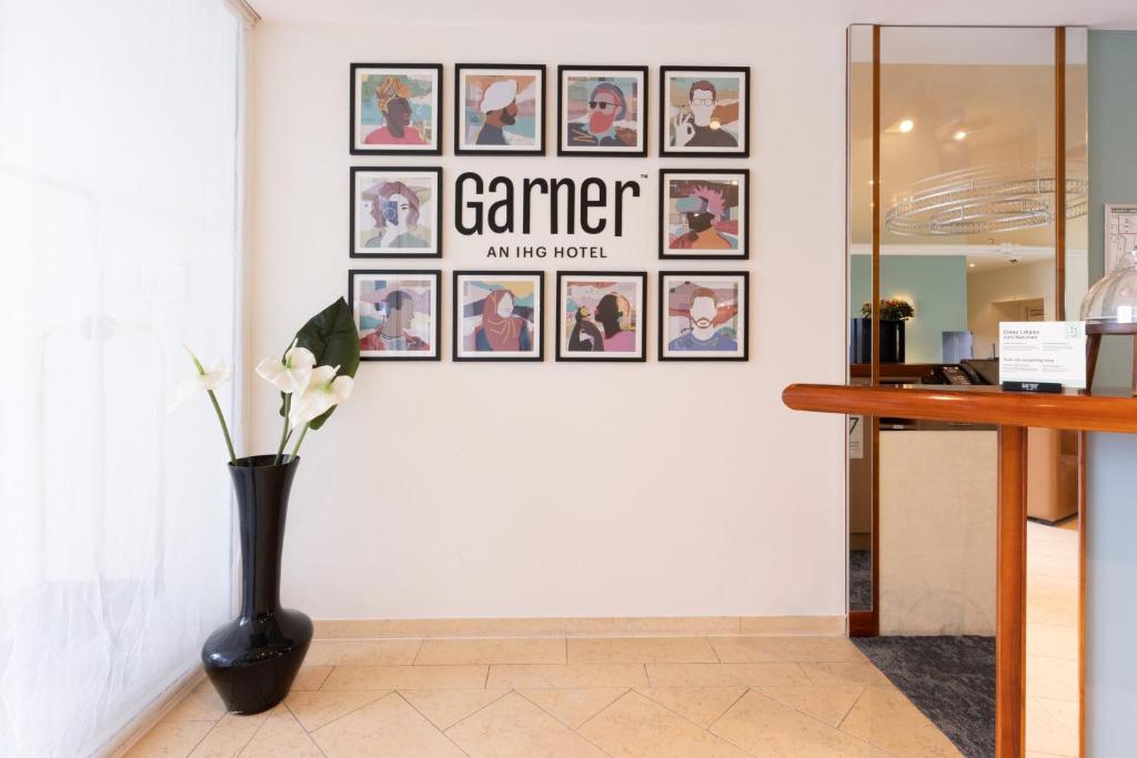 a gallery wall with pictures on a wall with a vase at Garner Hotel Post Aschaffenburg by IHG in Aschaffenburg