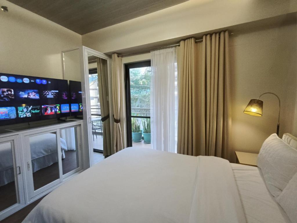 a bedroom with a large white bed and a television at 2-BR Condo near Major Tourist Spots in Baguio in Sampong