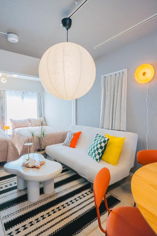 a living room with a white couch and orange chairs at Otter Stay Lite - Shinsakae in Nagoya