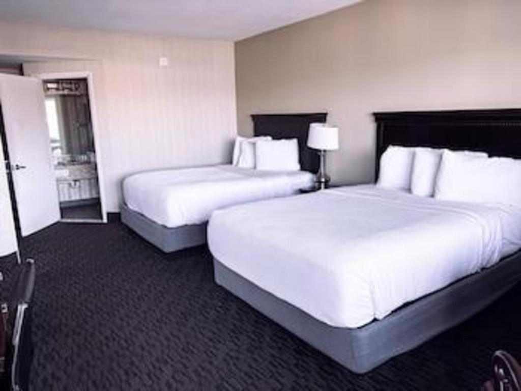 Dos camas en una habitación de hotel con sábanas blancas. en The Georgian Resort, en Lake George