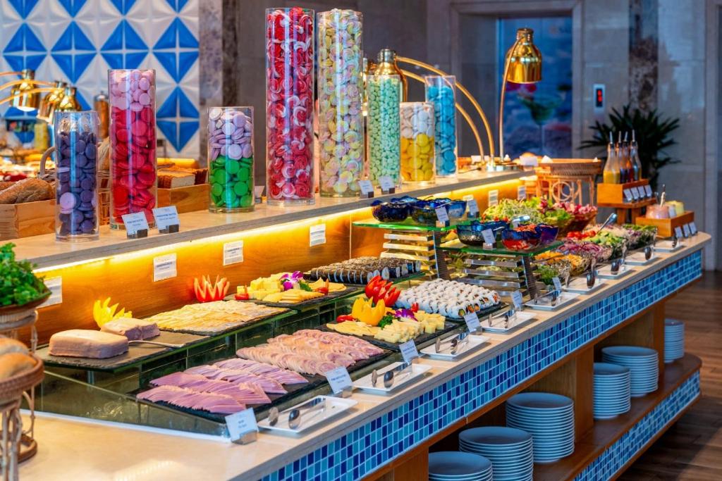 A long self-service buffet with cold cuts, cheese, vegetables and jars of snacks.