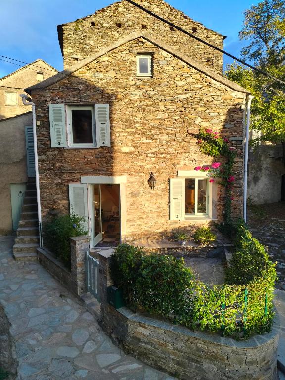 a brick house with a window and flowers on it at Maison corse - cap corse in Sisco