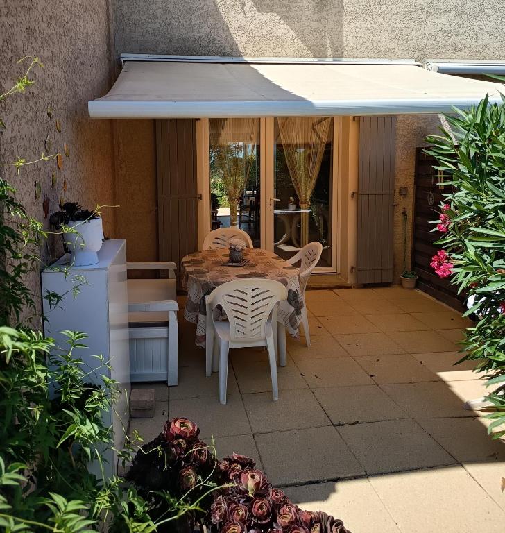 カルヴィッソンにあるMaison Le Poussinの傘の下にテーブルと椅子が置かれたパティオ